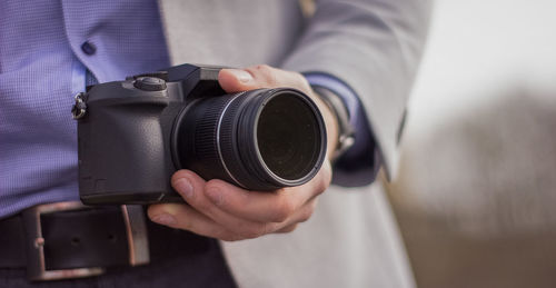 Midsection of man holding camera