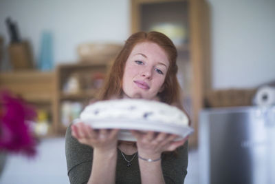 Young woman holding birthday cake in the hands at home