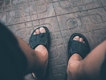 Low section of man wearing sandals on footpath