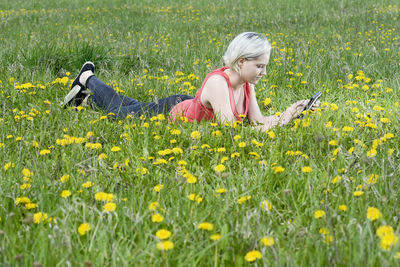 Full length of woman holding yellow flowers on field