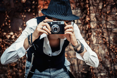 Photographer using retro photo camera while taking picture outdoors.