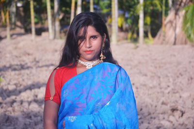 Portrait of girl wearing sari standing against trees