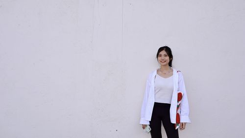 Portrait of woman standing against wall