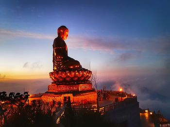 Statue at temple against sky during sunset