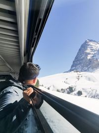 Rear view of man on snowcapped mountain against clear sky