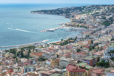 High angle view of cityscape by sea against sky