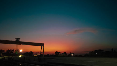 Silhouette street against sky during sunset