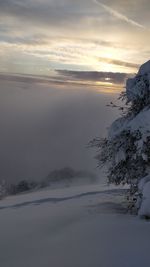 Scenic view of snow covered landscape against sky at sunset