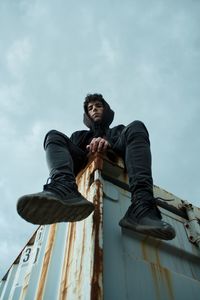 Low angle view of young man looking away against sky