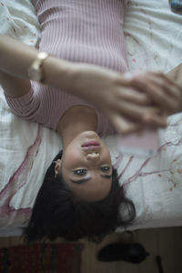 Young woman using her smartphone on her bed