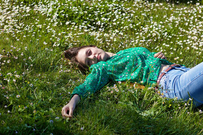 High angle portrait of young woman lying on grassy land