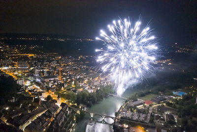 Firework display in city against sky at night