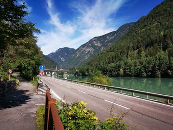 Road by trees and mountains against sky