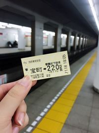 Cropped hand holding ticket at subway station