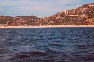 Scenic view of sea by townscape against sky