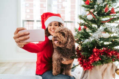 Woman with dog take photo on mobile phone at christmas day