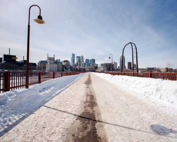 Street by road in city against sky