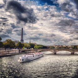 Bridge over river against cloudy sky