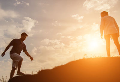 Side view of silhouette man standing against sky during sunset