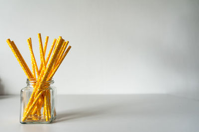 Close-up of yellow glass on table against white background