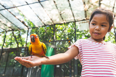 Girl with bird perching on hand