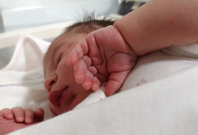 Close-up of baby girl lying on bed