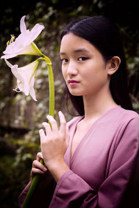 Asian teenage girl in purple blouse holding white flowers in her hands