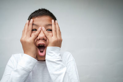 Close-up portrait of shocked boy against white background