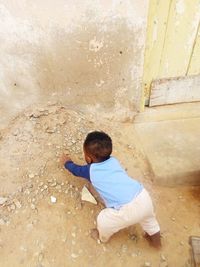 Rear view of boy sitting on wall