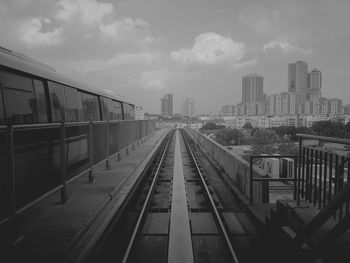 Railroad tracks amidst buildings in city against sky