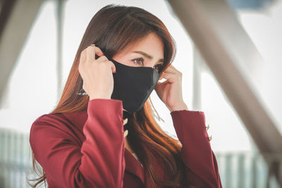 Portrait of young woman holding covering face