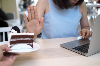 Midsection of woman using smart phone on table