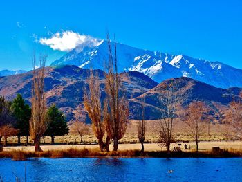 Scenic view of lake and mountains against blue sky