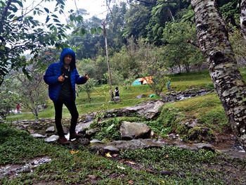 Full length of man standing on rock in forest