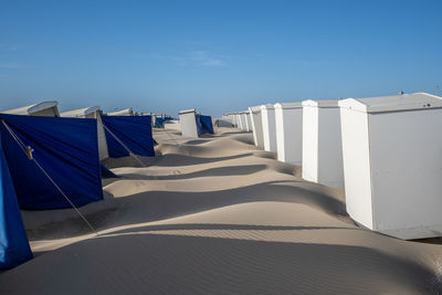 Row of chairs on beach against blue sky