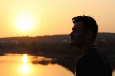 Side view of silhouette young woman against lake during sunset