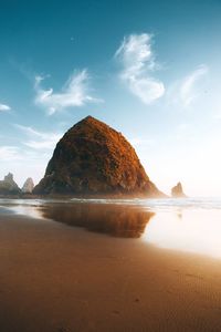 Rock formations at beach against sky