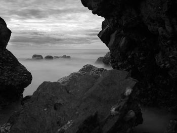 Long exposure of the ocean and rock scape with cloudy sky. black and white image.