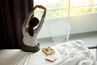 Rear view of woman relaxing on bed at home