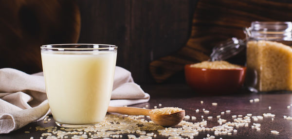 Lactose-free rice milk in a glass and rice cereal on the table web banner