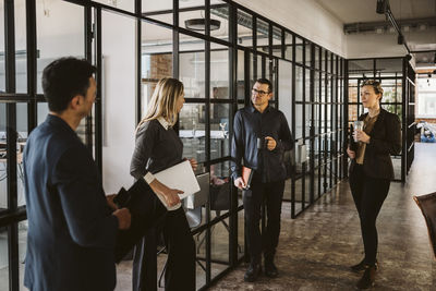 Female and male entrepreneurs discussing while standing at corridor in office