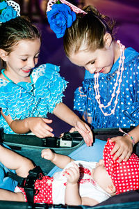 Portrait of happy girls playing with a  baby in flamenco costumes in summer feria at night