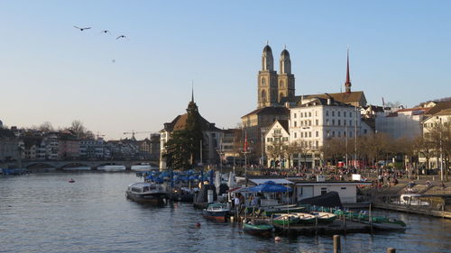 Boats in canal by buildings in city against sky