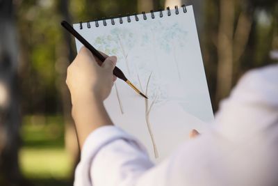 Midsection of woman painting over book