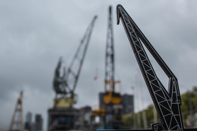 Low angle view of crane against cloudy sky