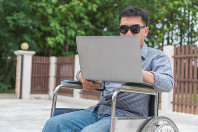 Man using mobile phone while sitting on laptop