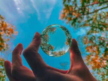 Close-up of human hand against sky