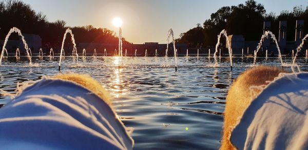 People by swimming pool against sky during sunset