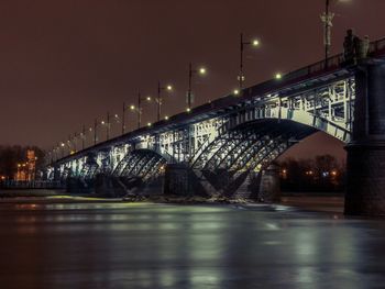 Illuminated bridge over river against sky at night