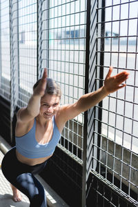 Full length of young woman sitting on window